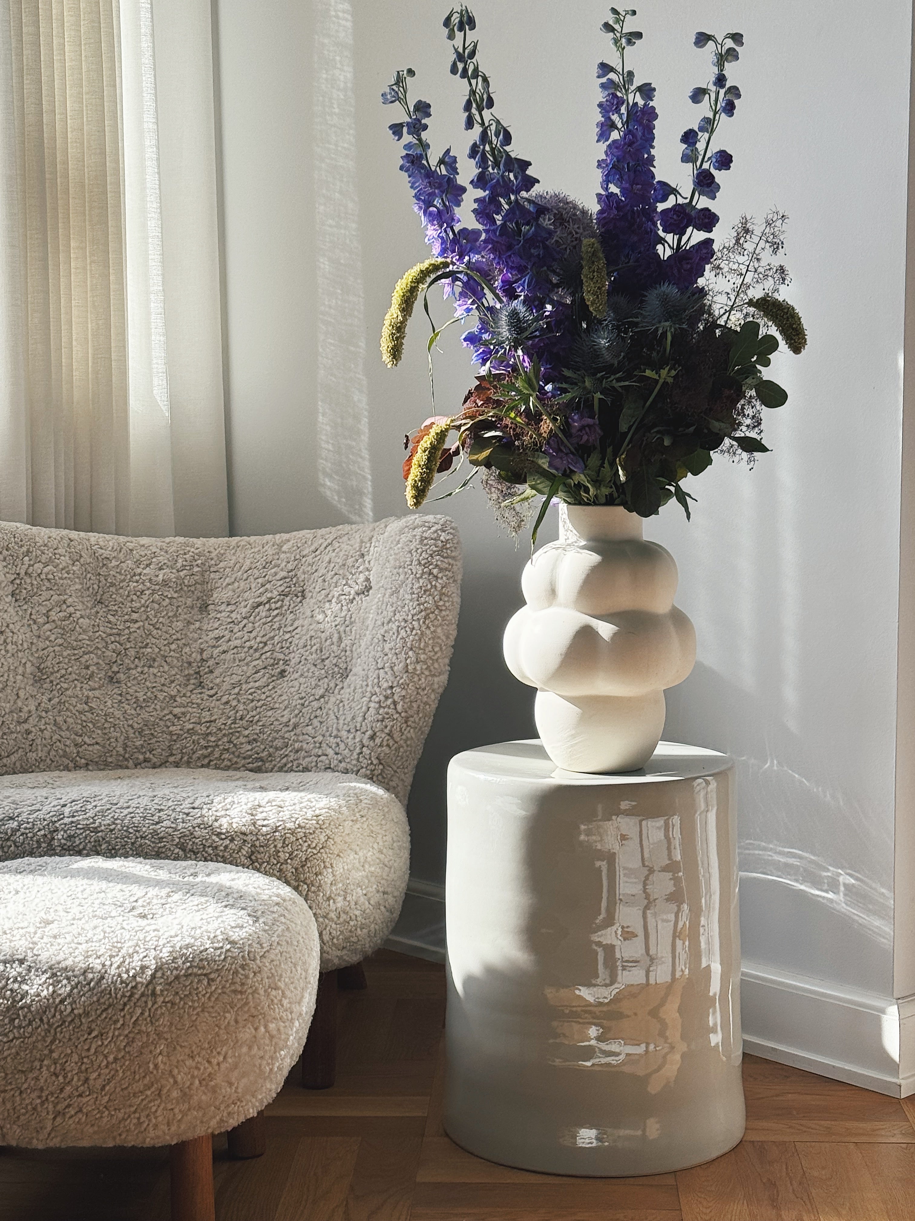 Modern ceramic side table in gray by Serax, styled with a sculptural vase and flowers in a contemporary living room