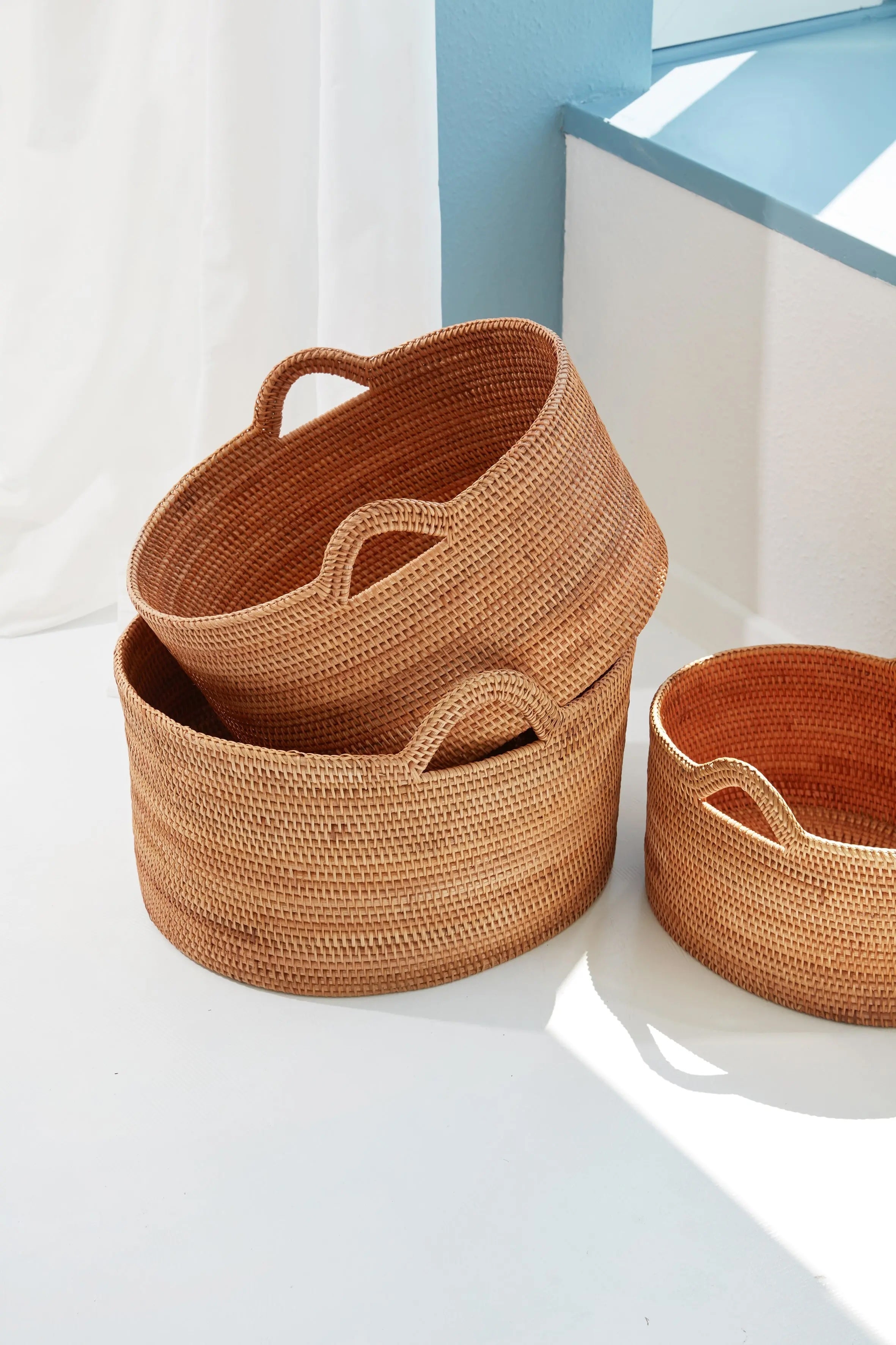 Set of three handmade rattan storage baskets with handles, natural woven design for home organization