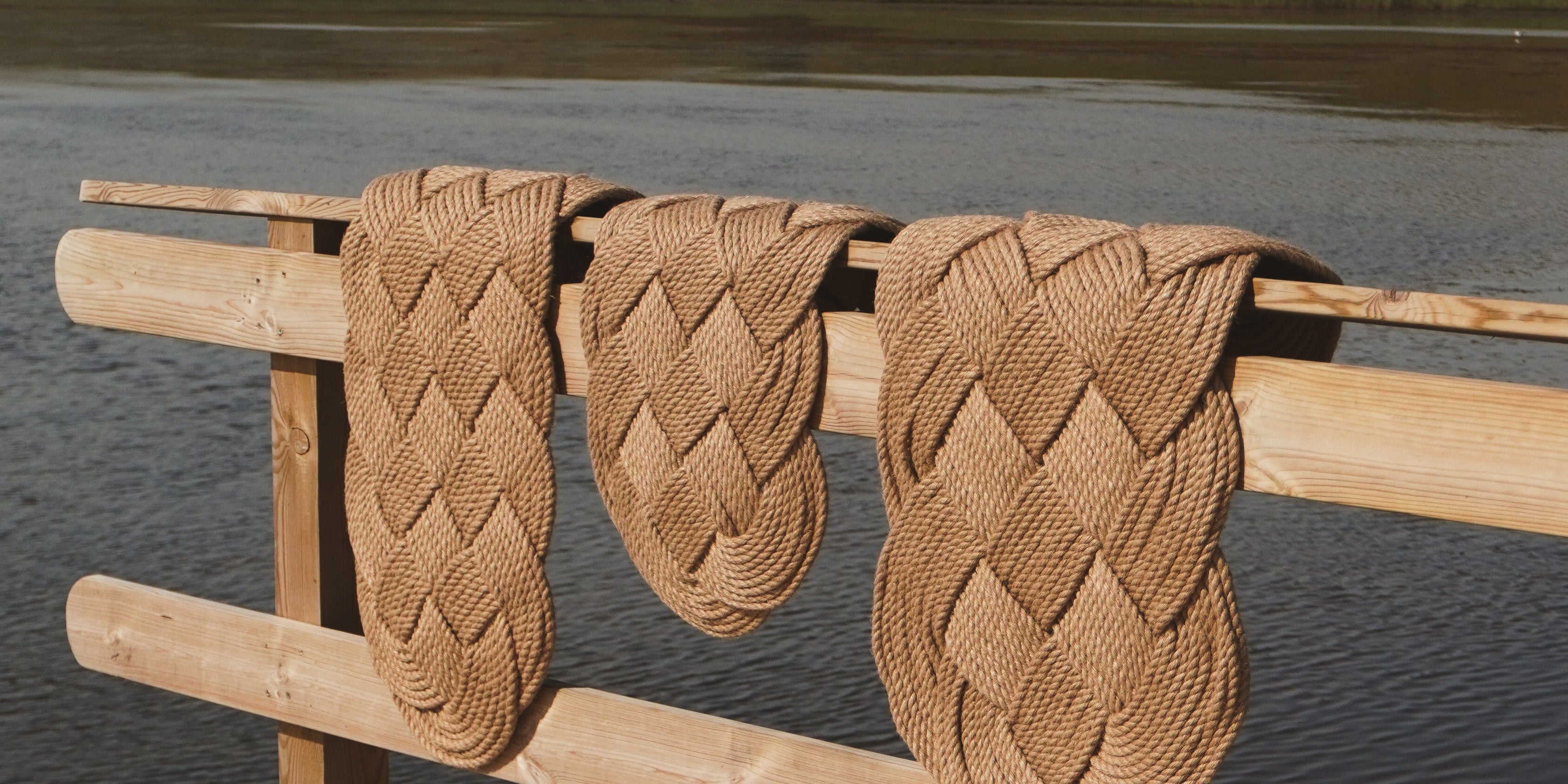 Ocean Plait doormats in hand-braided jute – three different sizes displayed on a wooden pier by the sea
