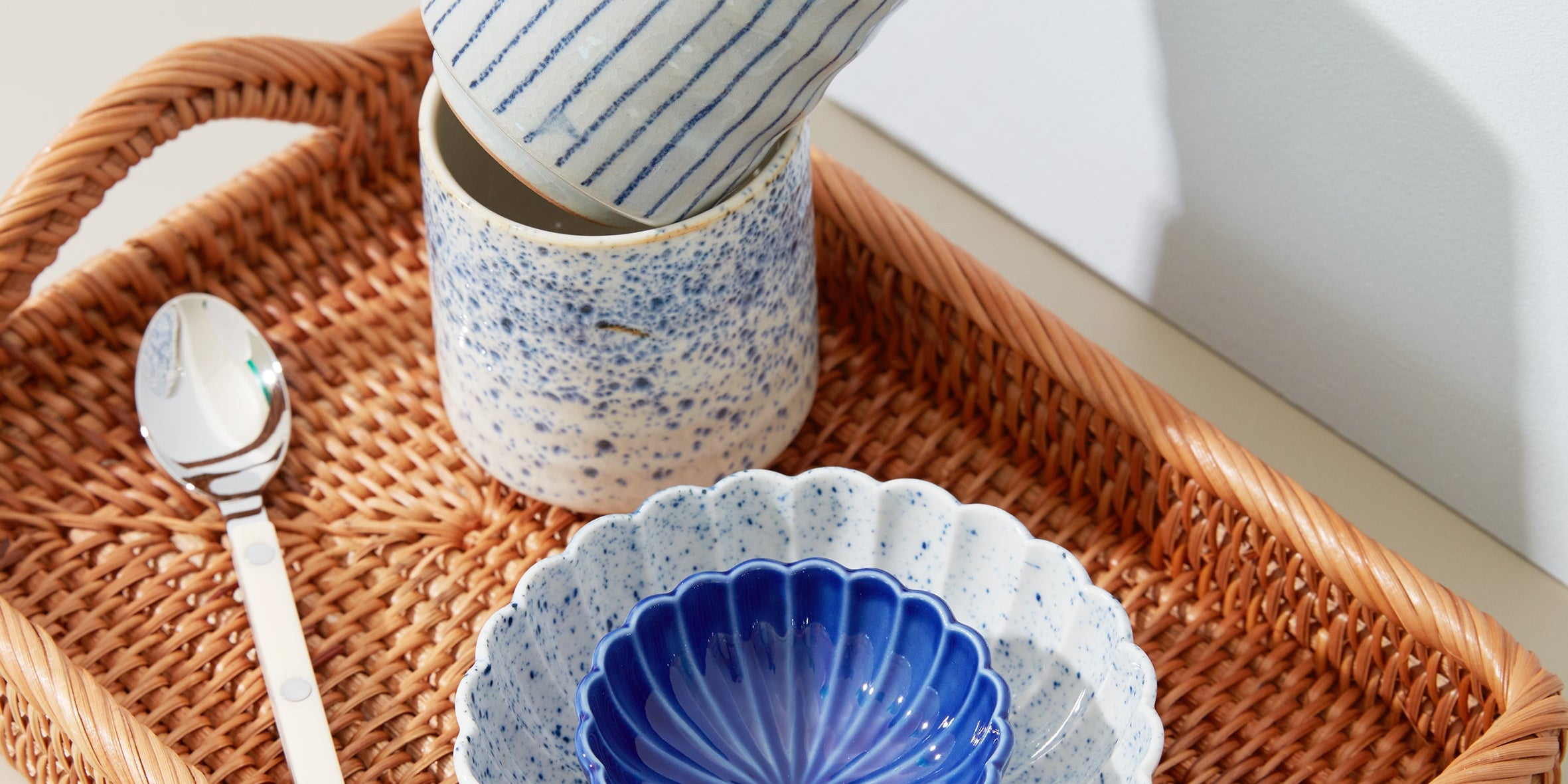 Rattan tray with Japanese ceramic bowls and cups in blue and white – elegant tableware and kitchen accessories.