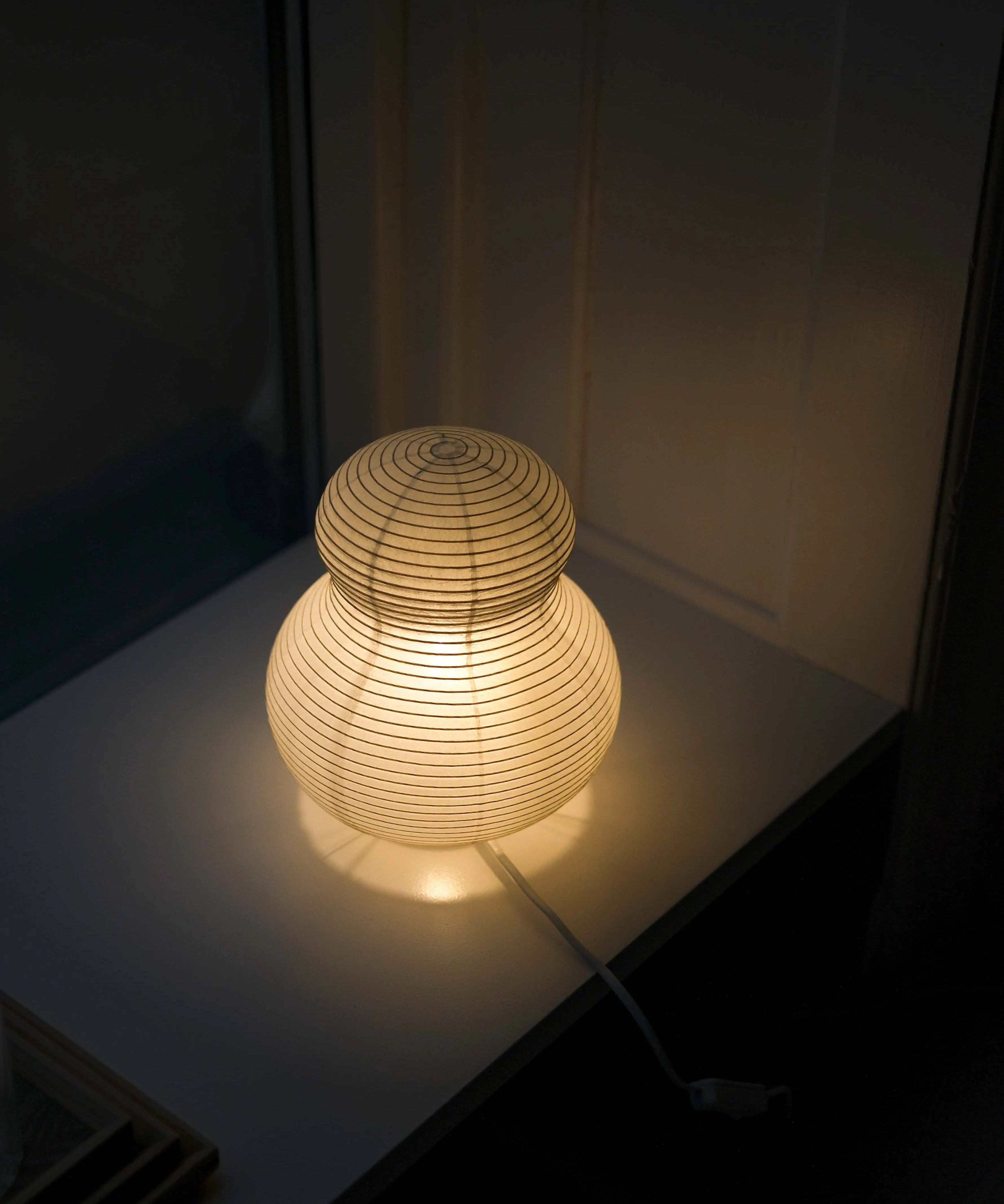 Tændt Asano Paper Moon PM02 papirlampe i washi med varmt lys i et mørkt rum