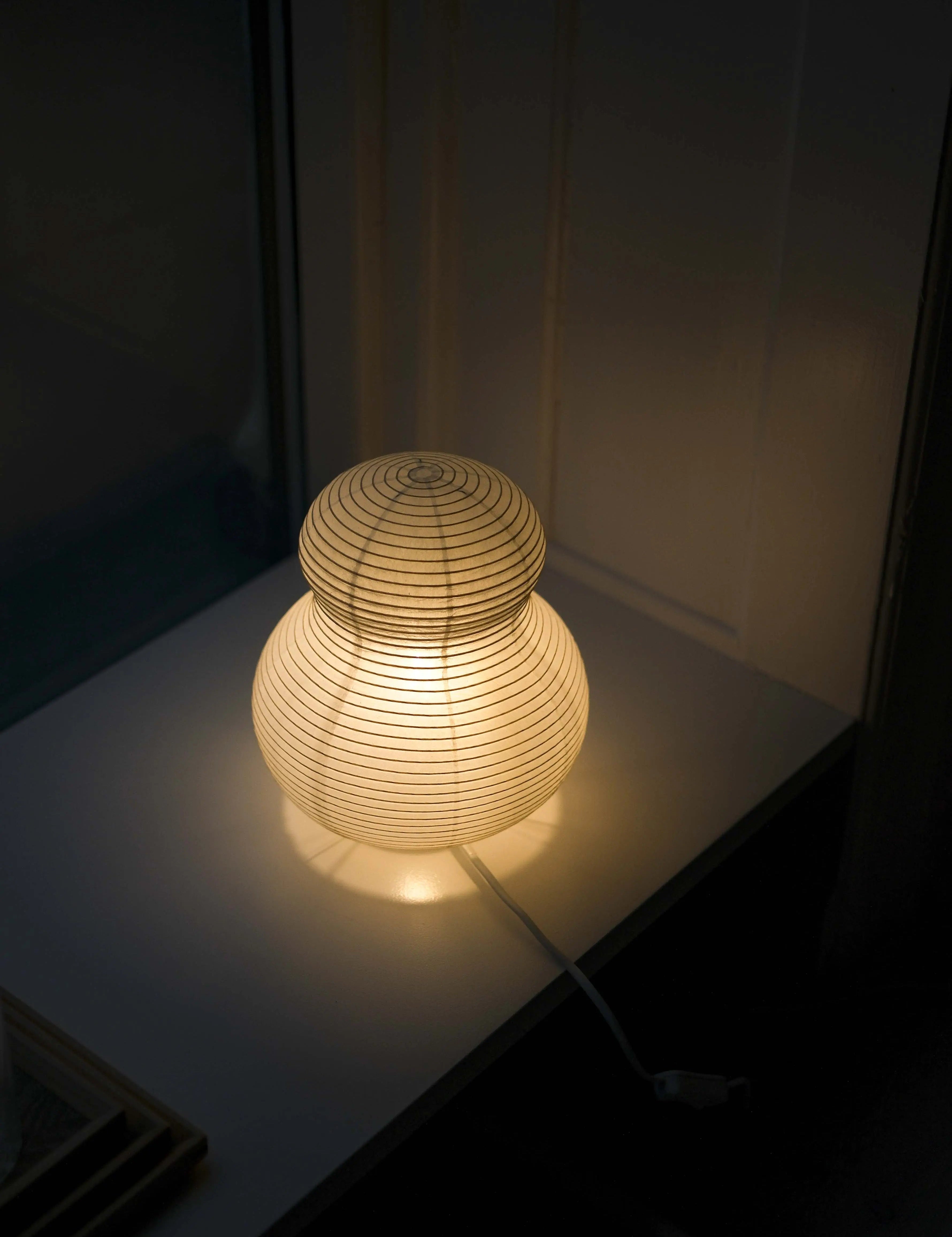 Tændt Asano Paper Moon PM02 papirlampe i washi med varmt lys i et mørkt rum