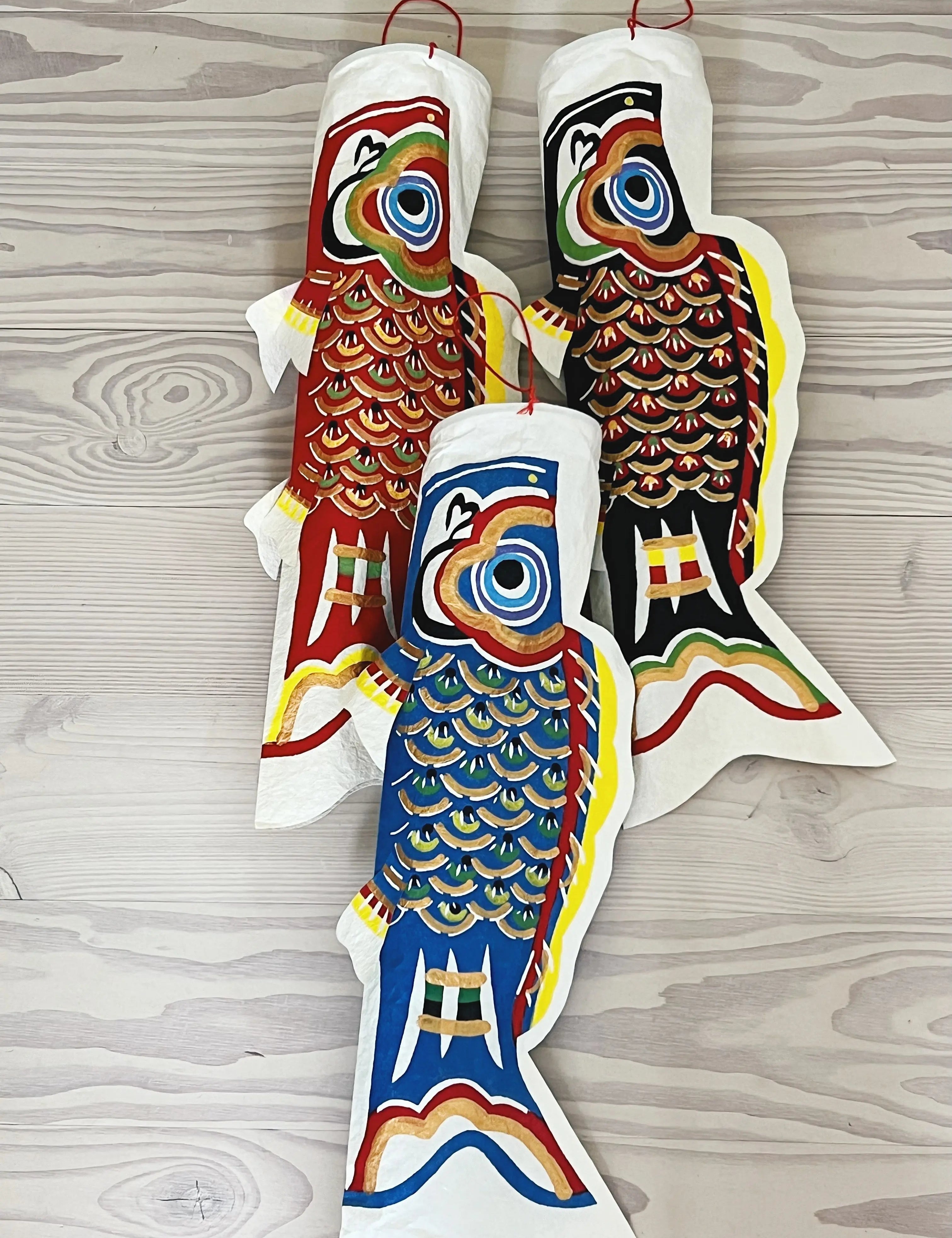 Three hand-painted Koi Koinobori fish in washi paper – red, blue, and black Japanese decorative hangings symbolizing strength, luck, and family.