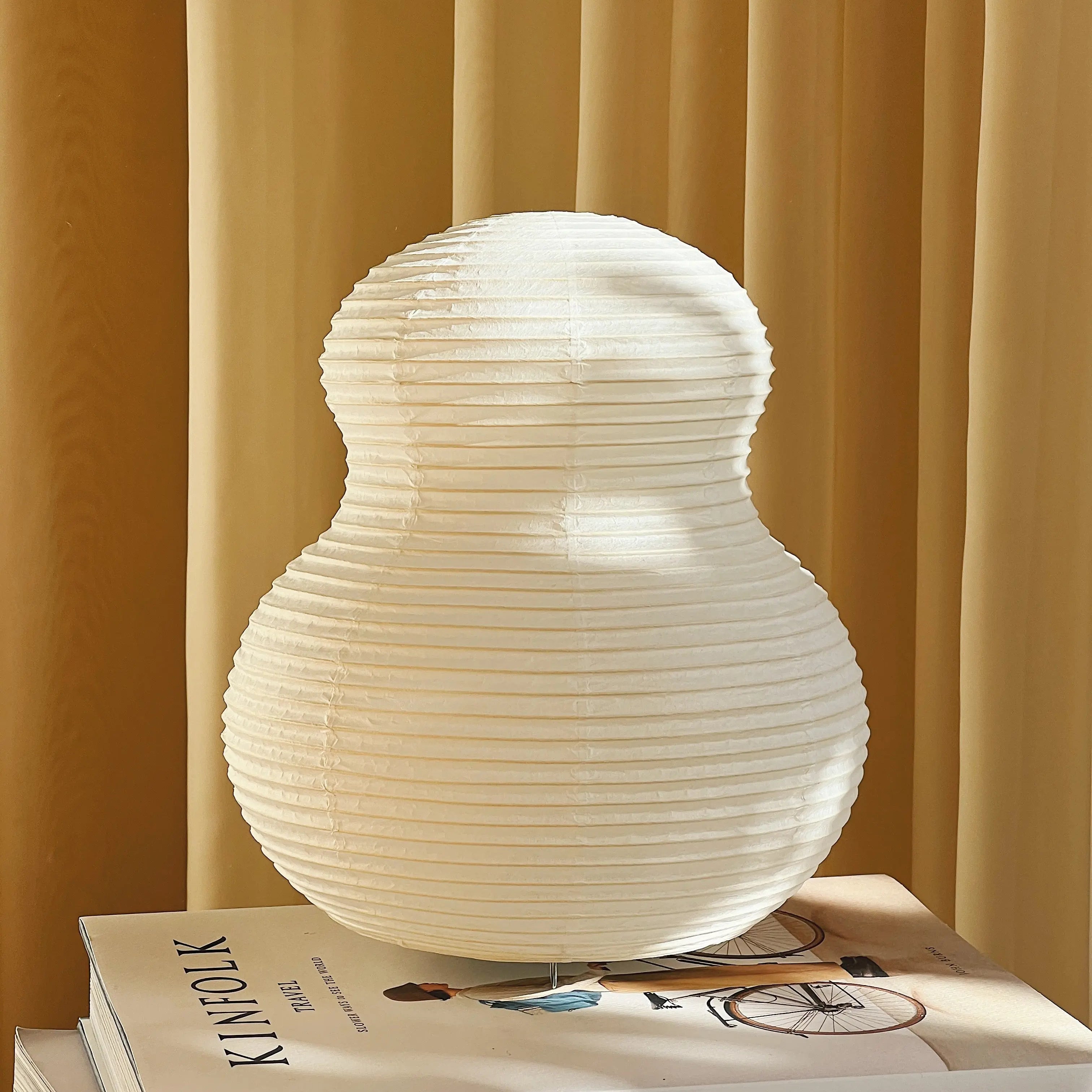 Paper Moon table lamp by Shigeru Uchida – Japanese washi paper lamp with sculptural design, photographed on books in warm natural light.