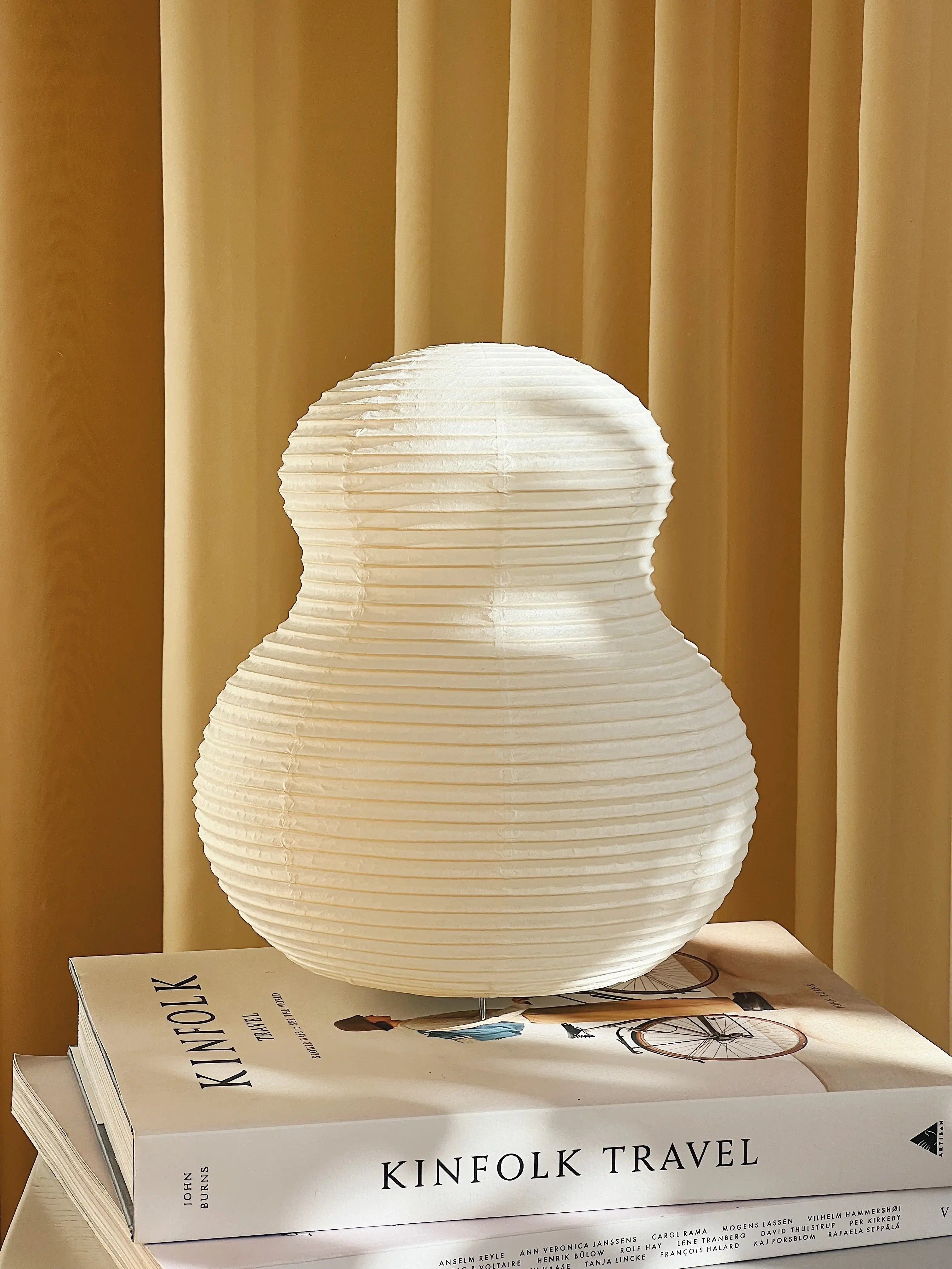 Paper Moon table lamp by Shigeru Uchida – Japanese washi paper lamp with sculptural design, photographed on books in warm natural light.
