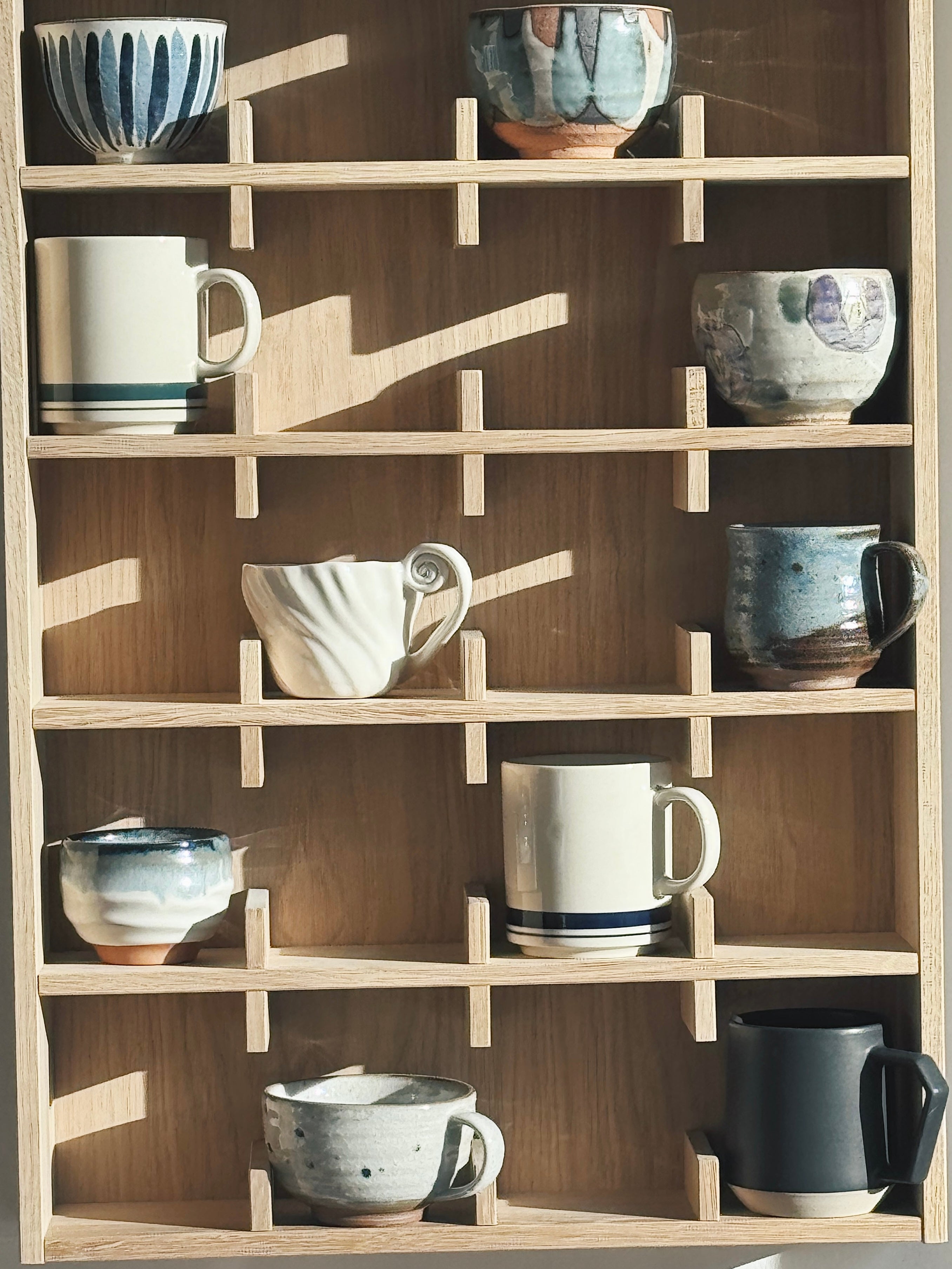 Krus og kopper i keramik med og uden hank på træhylde
