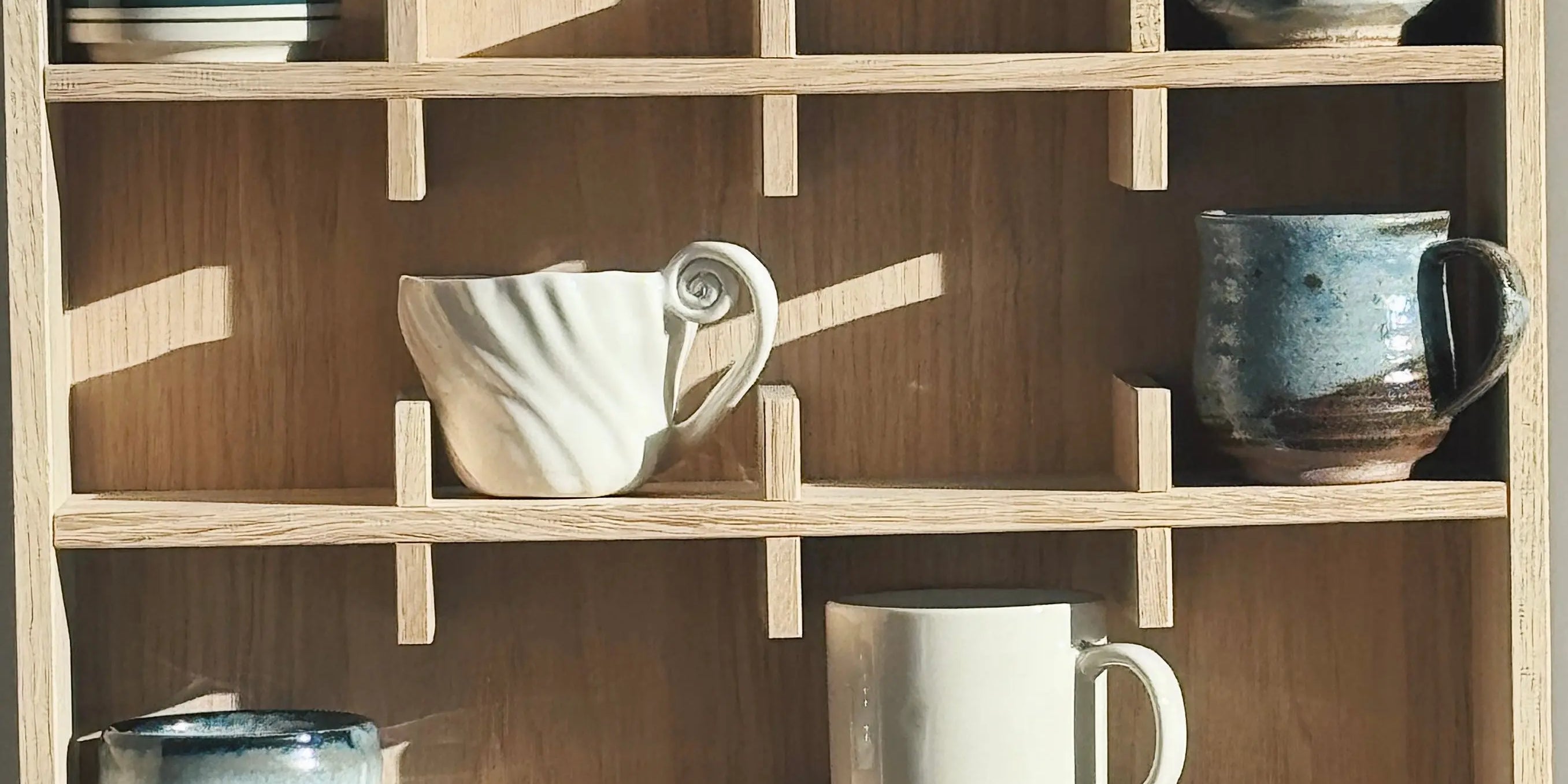 Krus og kopper i keramik med og uden hank på træhylde