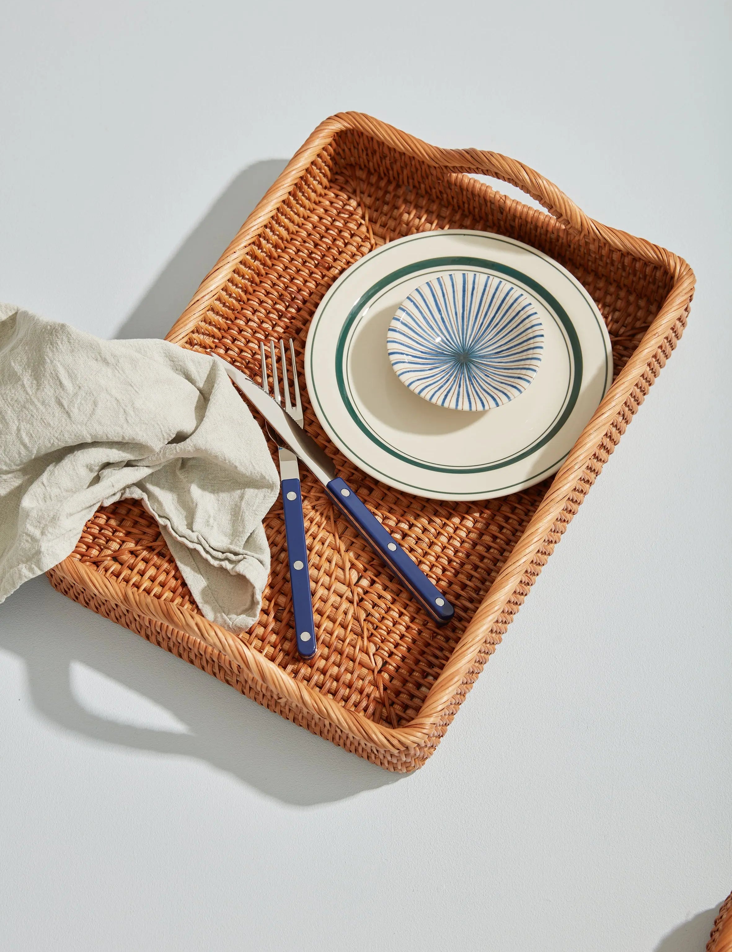 Rattan serving tray styled with Japanese ceramic plates and blue cutlery – handmade tray for elegant dining and kitchen use.