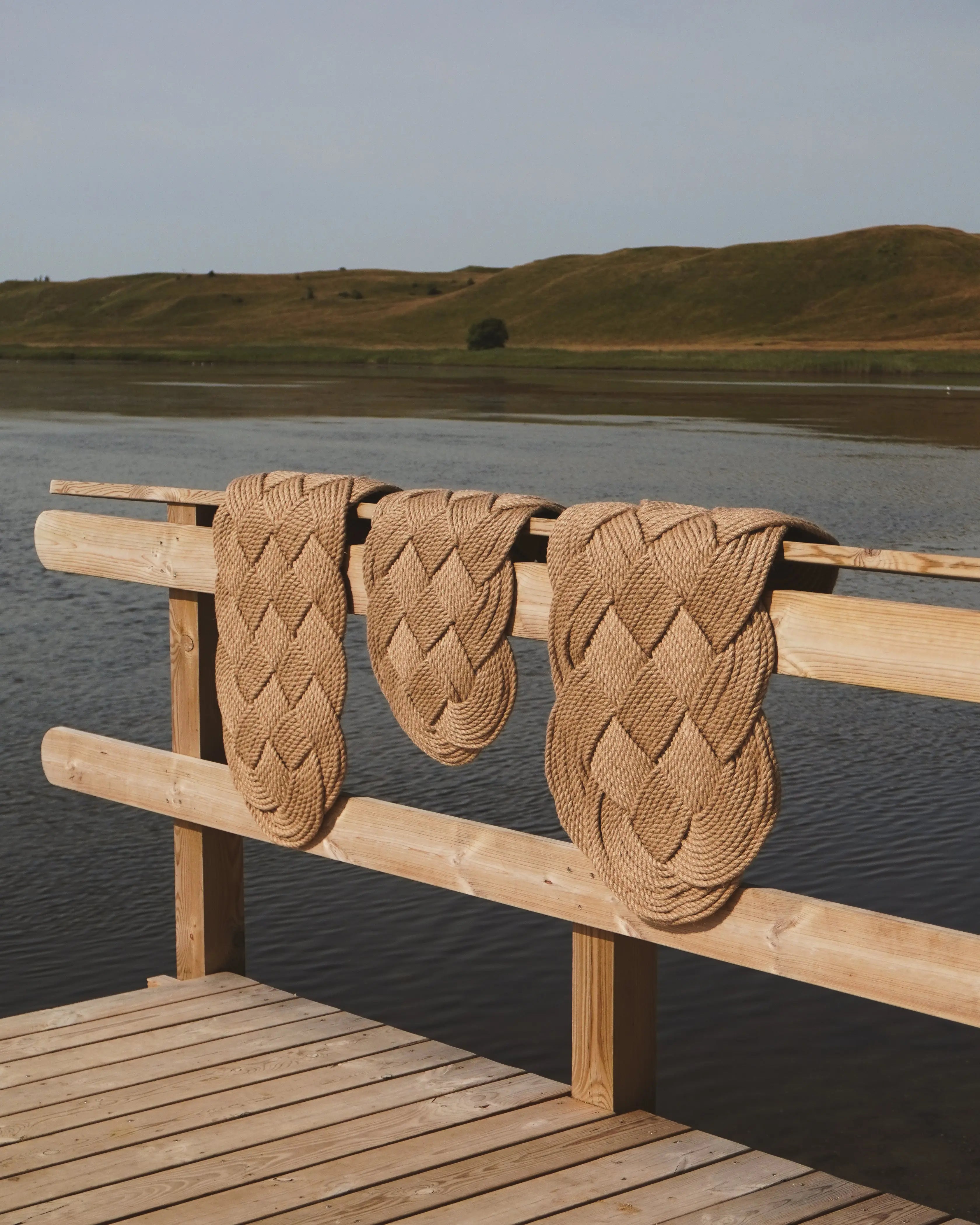 Ocean Plait doormats in hand-braided jute – three different sizes displayed on a wooden pier by the sea