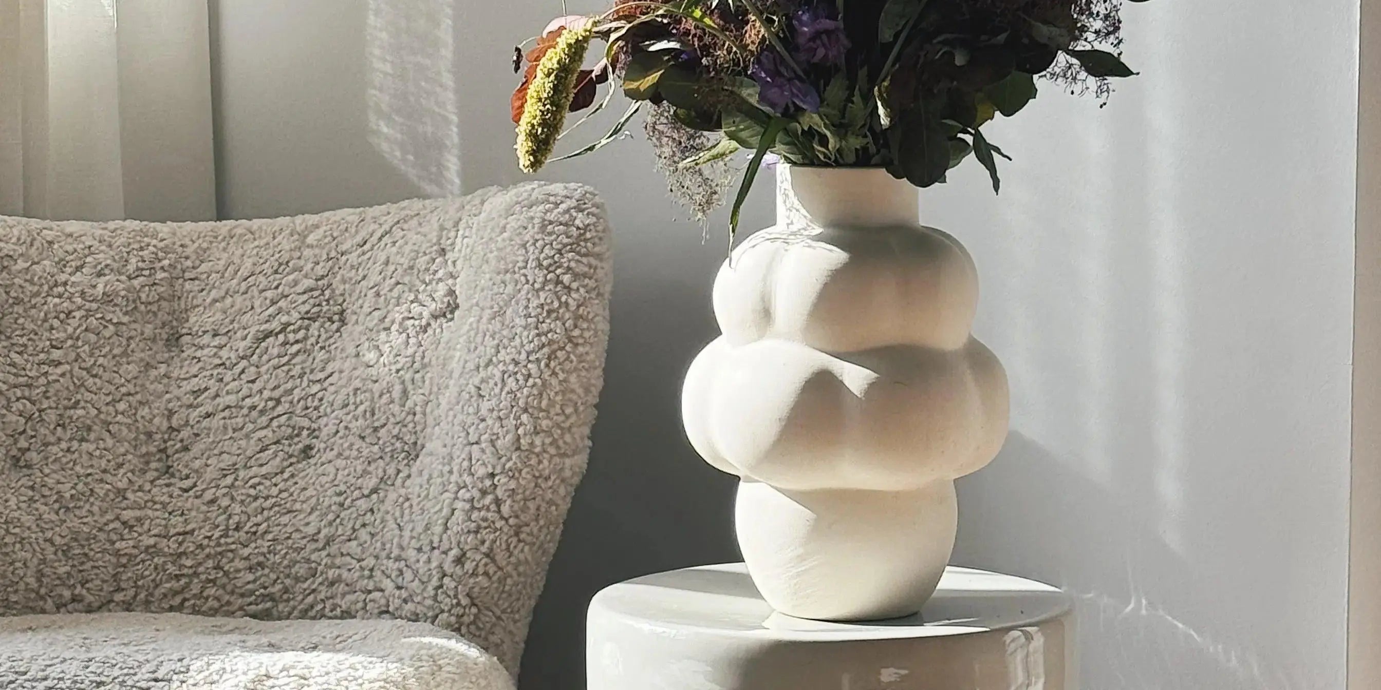 Josephine glass jar with lid by Serax, clear glass design displayed on pedestal with warm beige curtain background