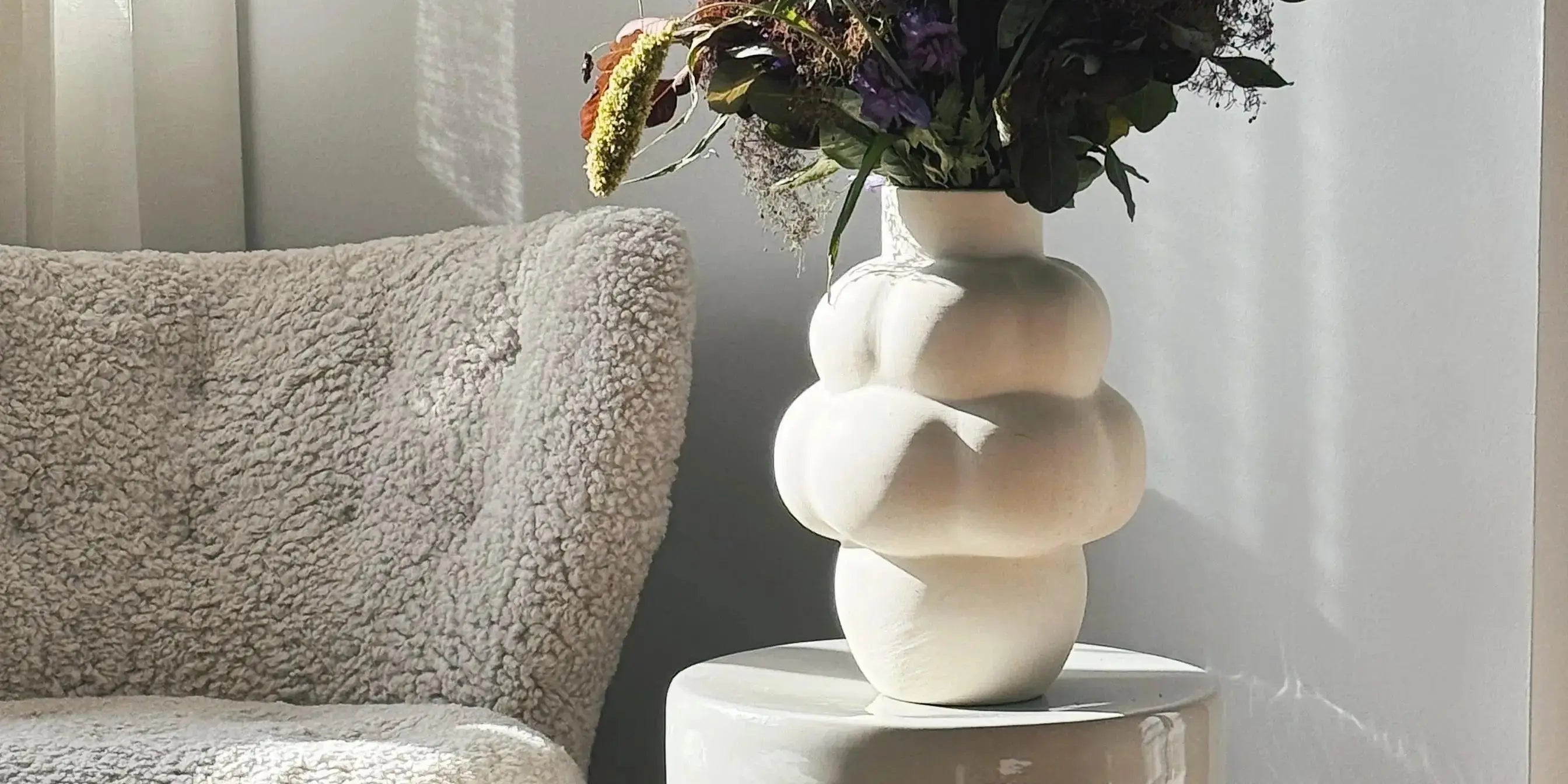 Josephine glass jar with lid by Serax, clear glass design displayed on pedestal with warm beige curtain background