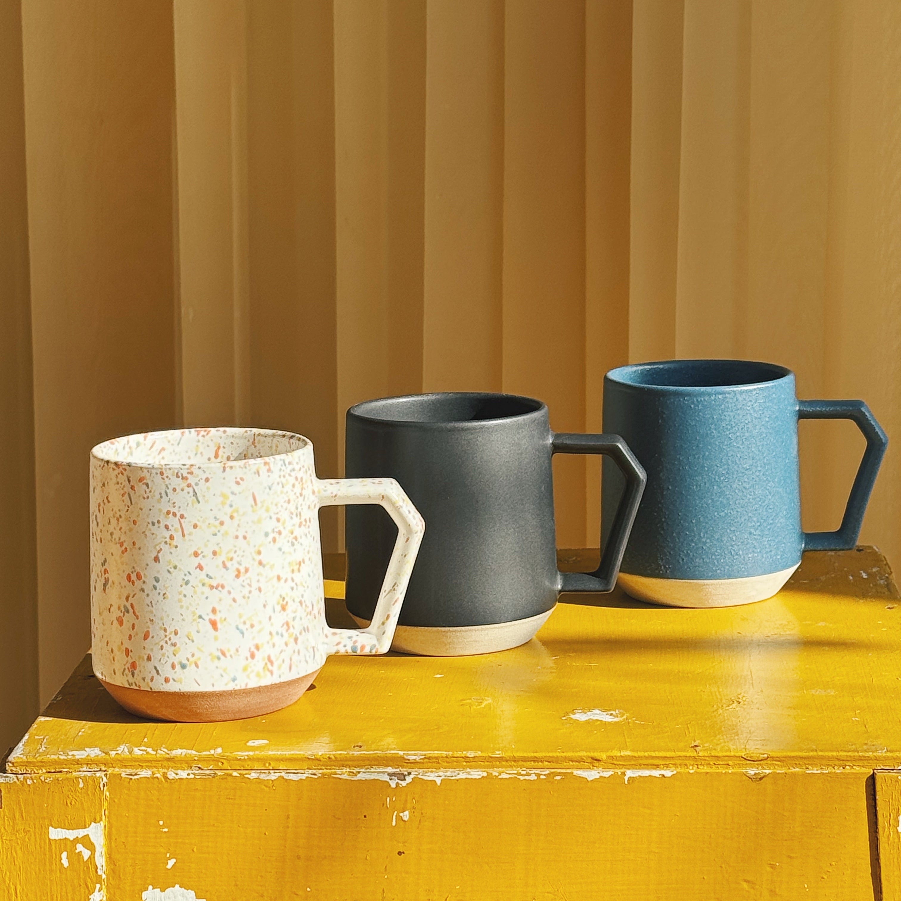 Three Chips Japan mugs in Minoyaki porcelain in different colors on a yellow chair – Japanese stackable cups available at Studio Hafnia.