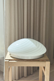 Hvid Murano swirl plafondlampe Ø36 cm på egetræsbord med gardin i baggrunden