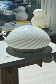 White Murano swirl plafond lamp Ø34 cm styled on a table in an interior