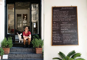 Spread from Atelier September with a man and dog on the steps outside the café and a handwritten menu board on a white wall