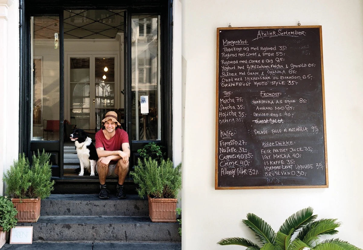 Spread from Atelier September with a man and dog on the steps outside the café and a handwritten menu board on a white wall