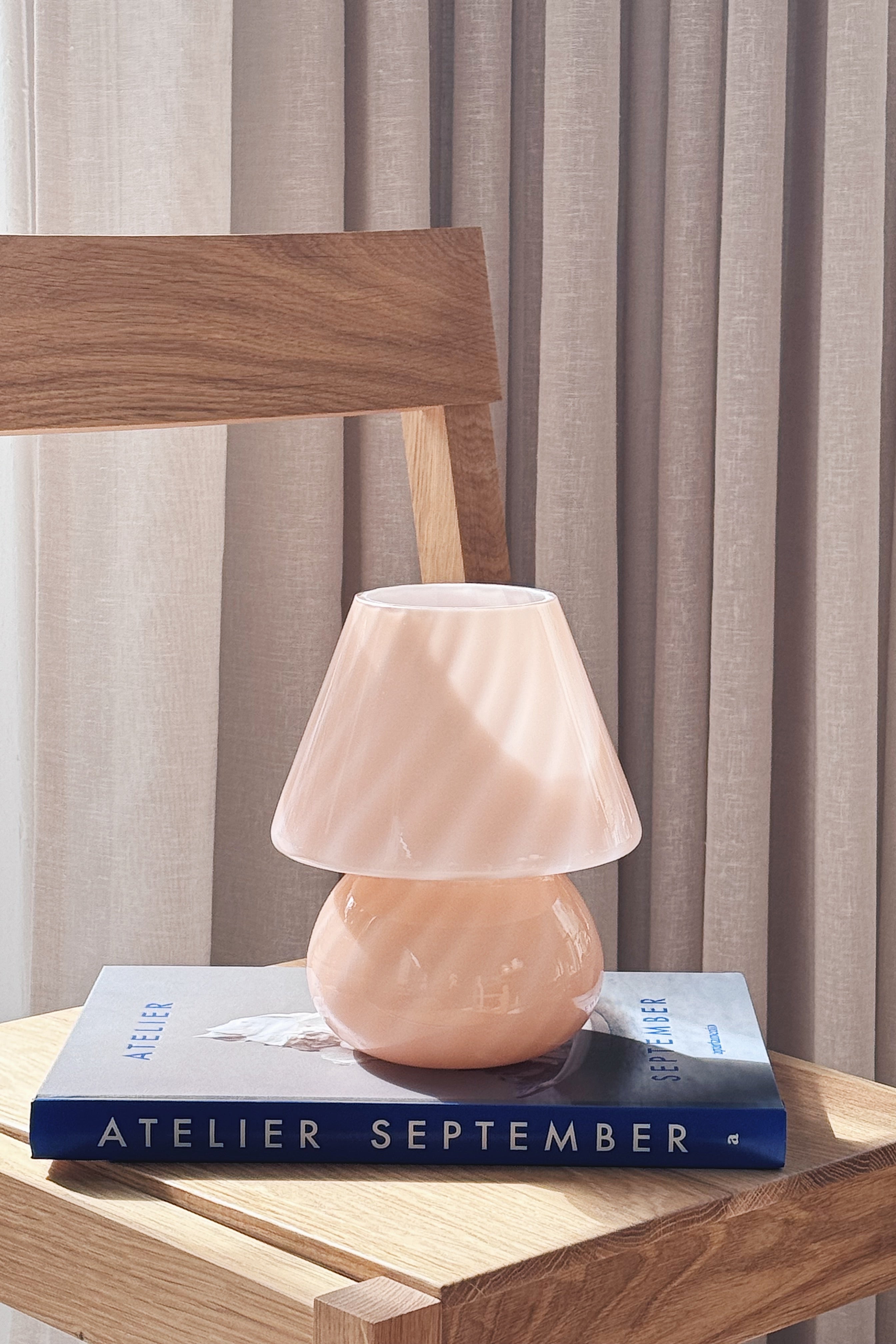 Small pink Murano mushroom lamp in mouth-blown glass resting on a book