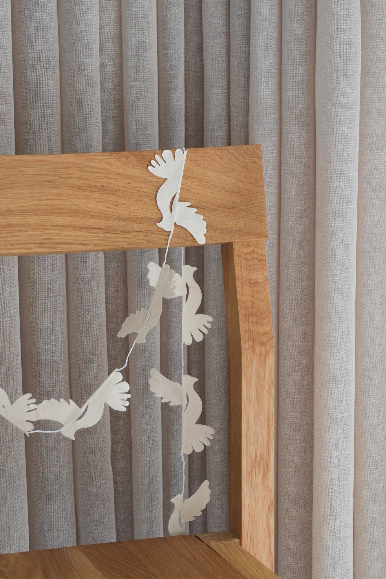 Dove paper garland with white birds hung over an oak chair back