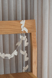 Dove paper garland with white birds hung over an oak chair back
