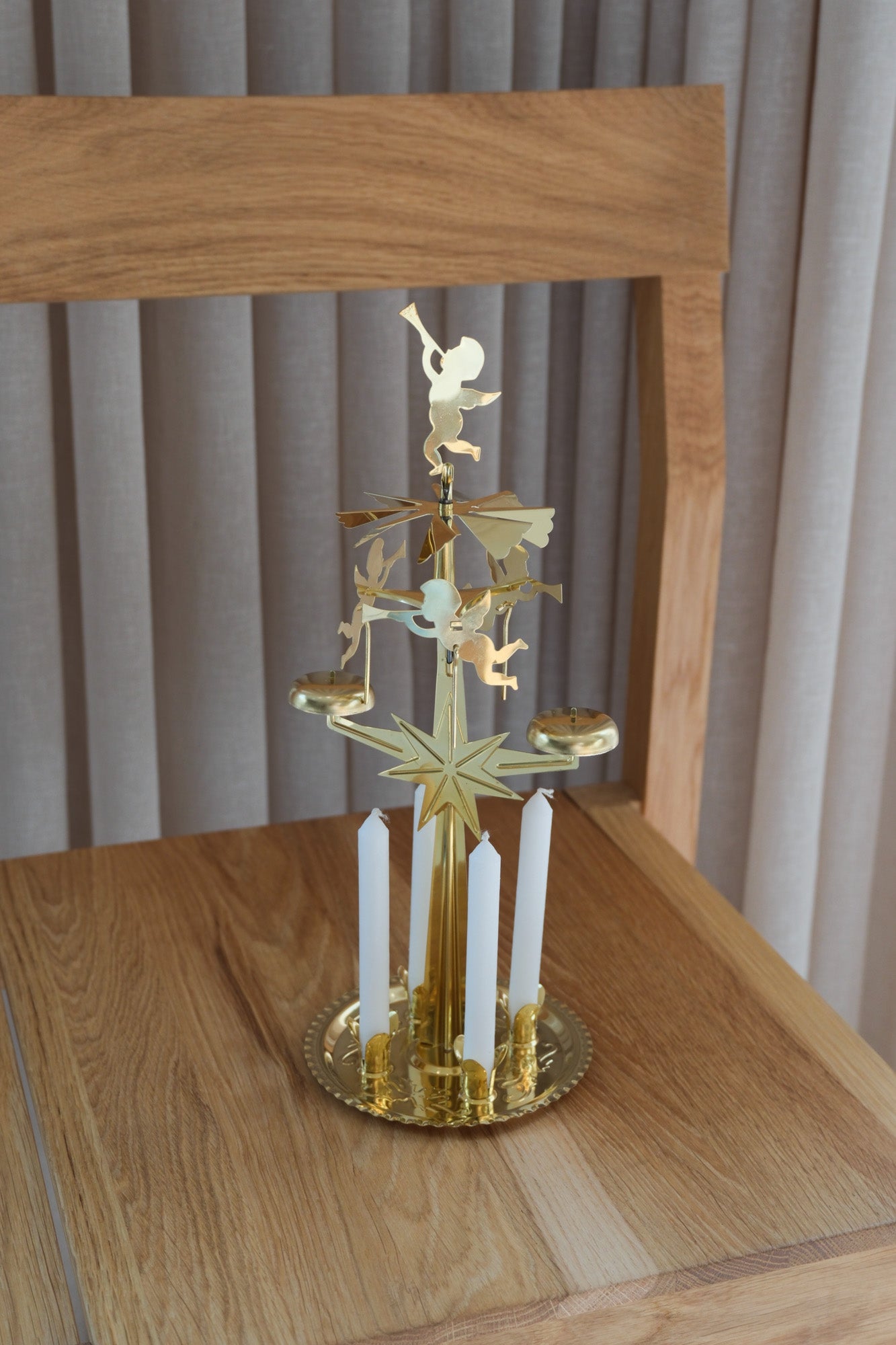Swedish brass angel chime with angels, star and 4 white candles on an oak chair