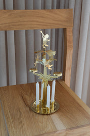 Swedish brass angel chime with angels, star and 4 white candles on an oak chair