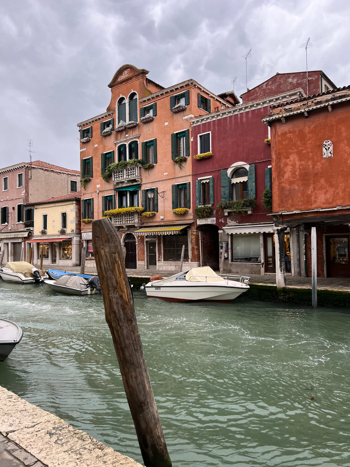 Kanal på Murano ved Venedig med pastelfarvede huse og fortøjede både