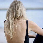 Inger necklace in 14 carat gold worn with a black swimsuit by the water