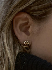 Close-up of the Inger earring in solid 14 carat gold in the ear, with sculptural hollows