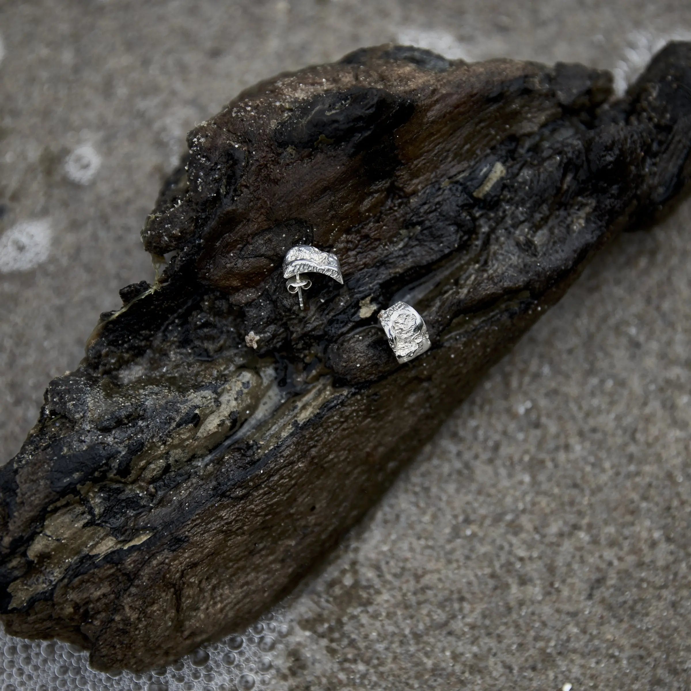 Inger Earrings in solid 925 sterling silver on driftwood by the water, with an organic water-worn surface