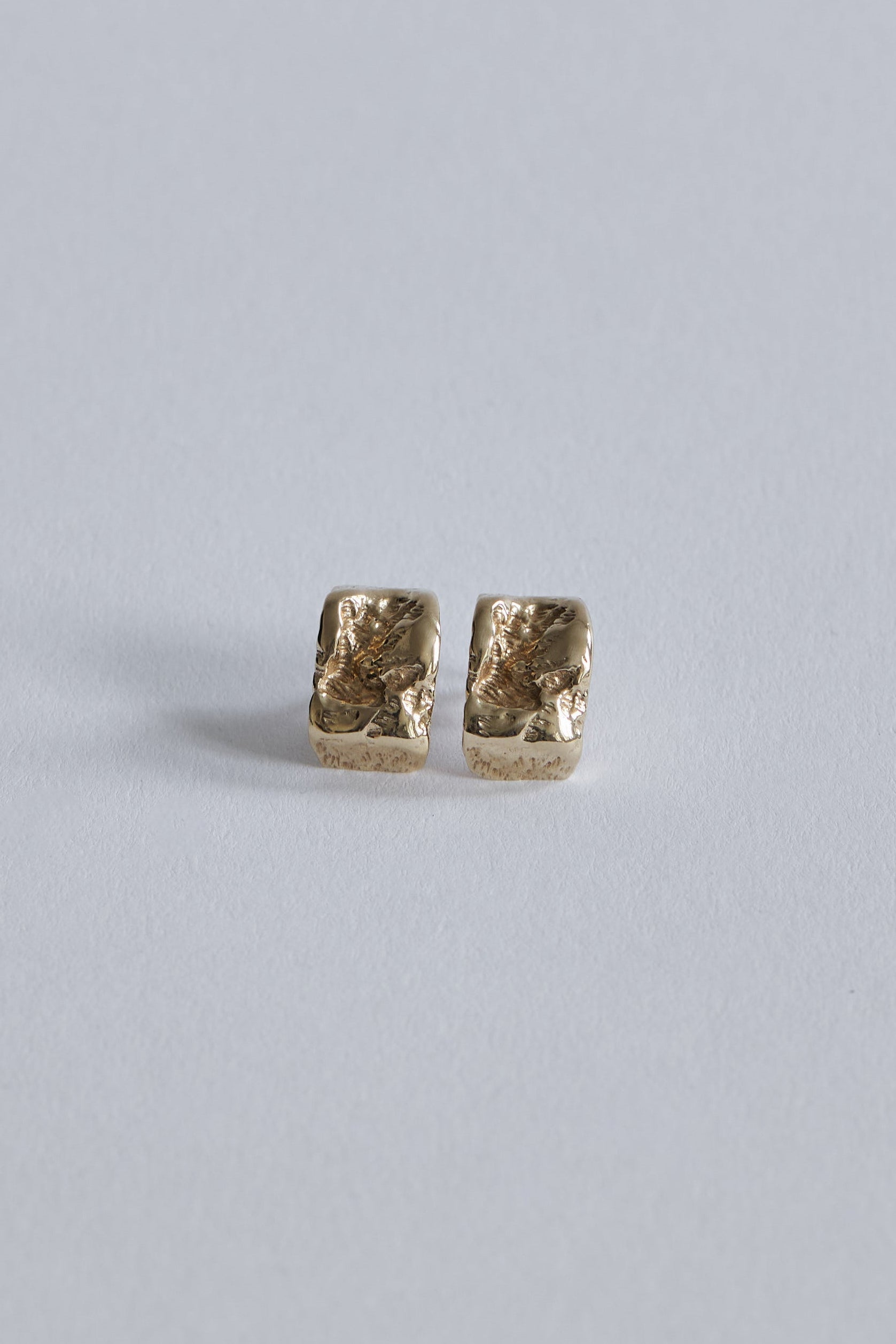 Inger Øreringe i 14 karat guld set tæt på med skulpturelle fordybninger i overfladen