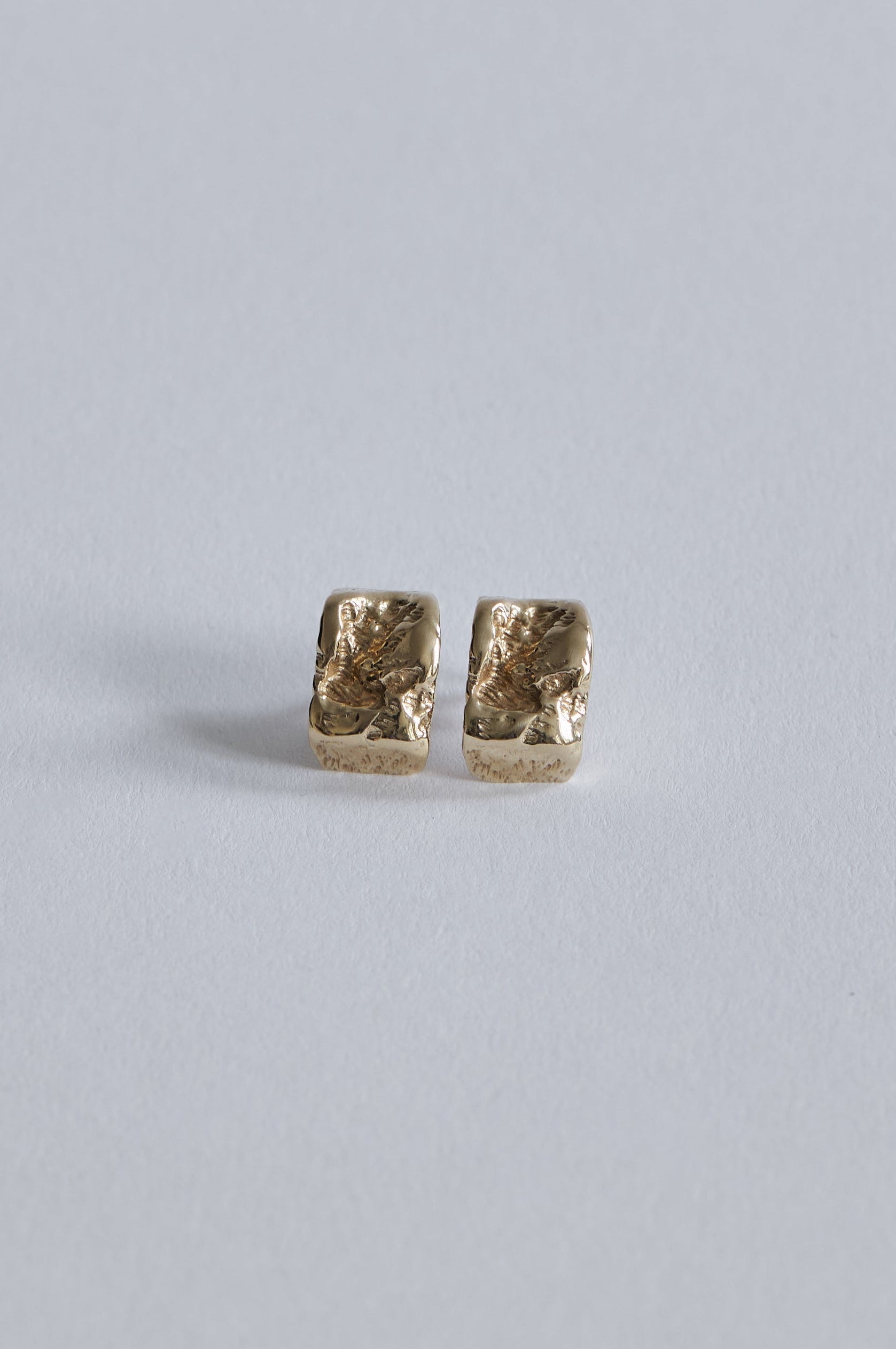 Inger Øreringe i 14 karat guld set tæt på med skulpturelle fordybninger i overfladen