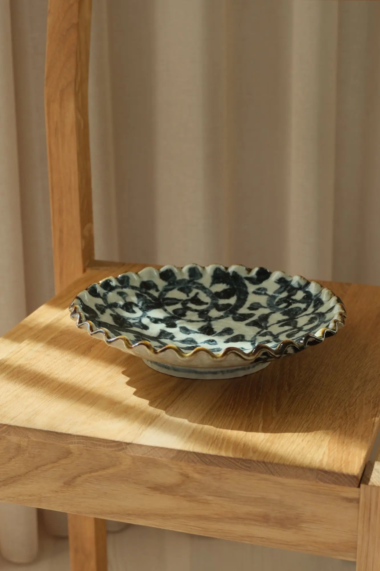 Japanese hand-painted dish in white ceramic with a dark blue pattern and brown edge.





