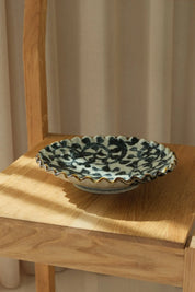 Japanese hand-painted dish in white ceramic with a dark blue pattern and brown edge.





