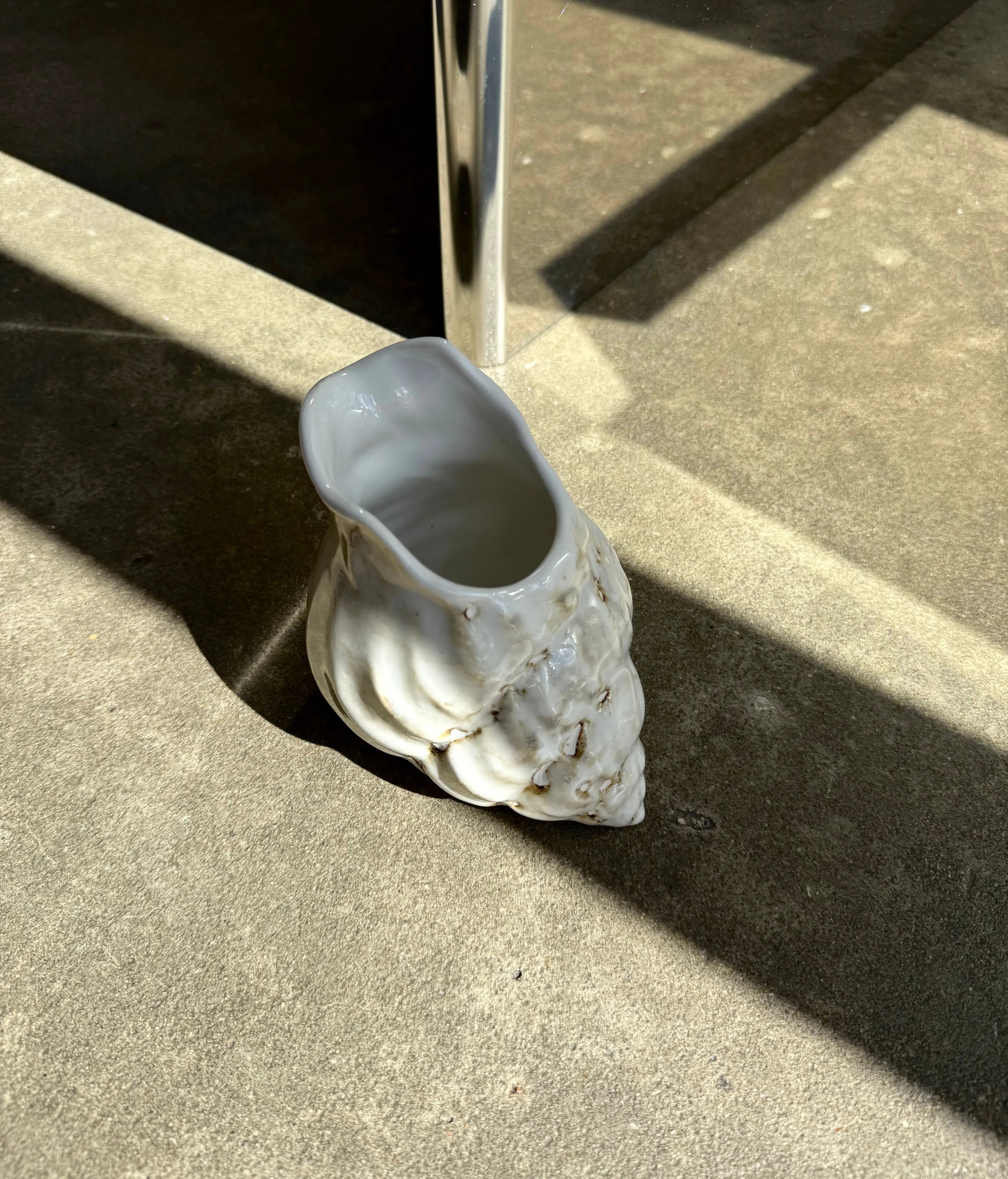 Conch Jug in cream ceramic from Christina Iversen Studio in strong sunlight on a concrete floor