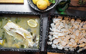 Bagt hvid fisk med citron og mandelflager i emaljefade i restaurantkøkkenet