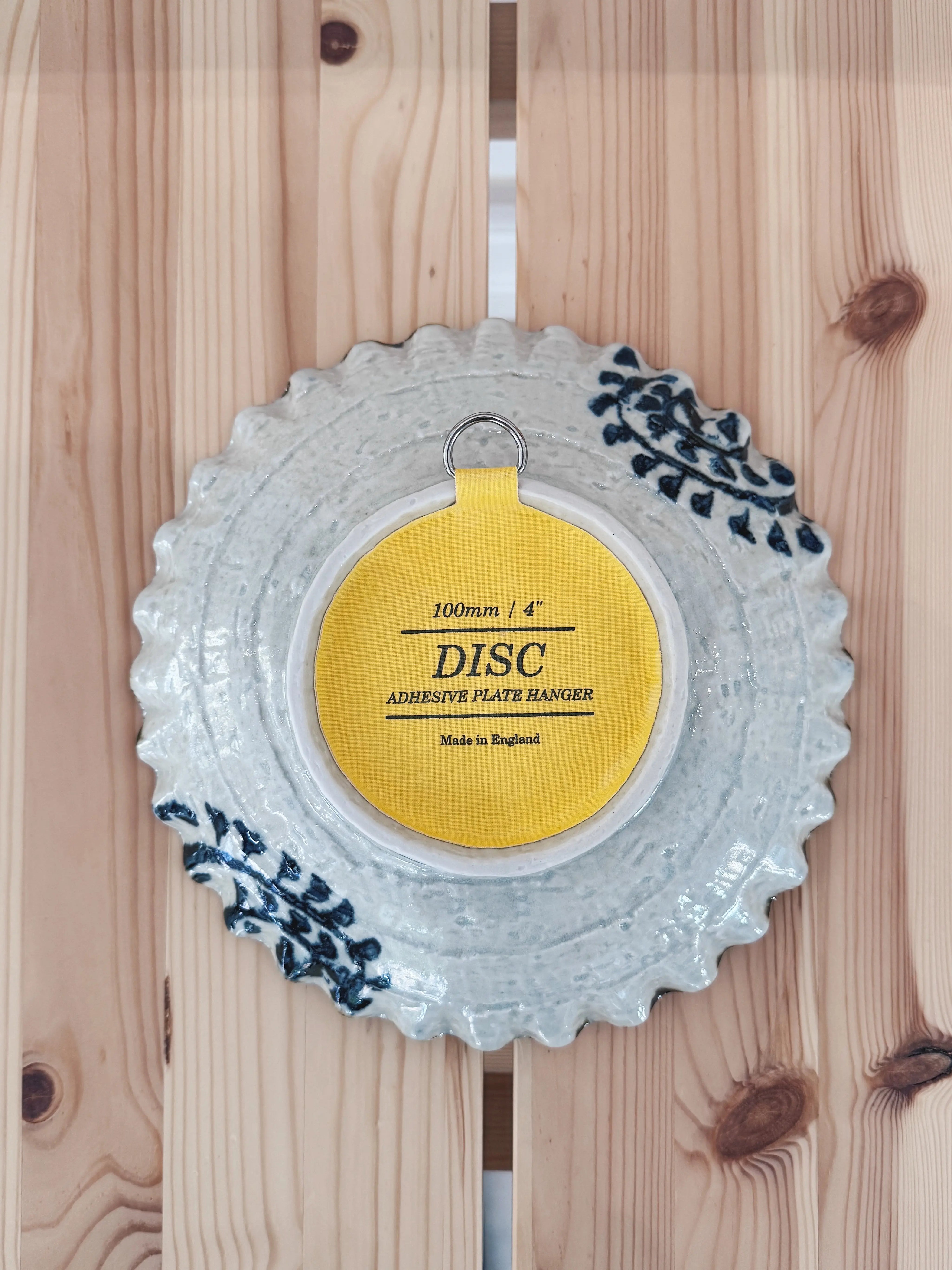 White plate with hand-painted blue pattern, suited for hanging with an invisible plate hanger