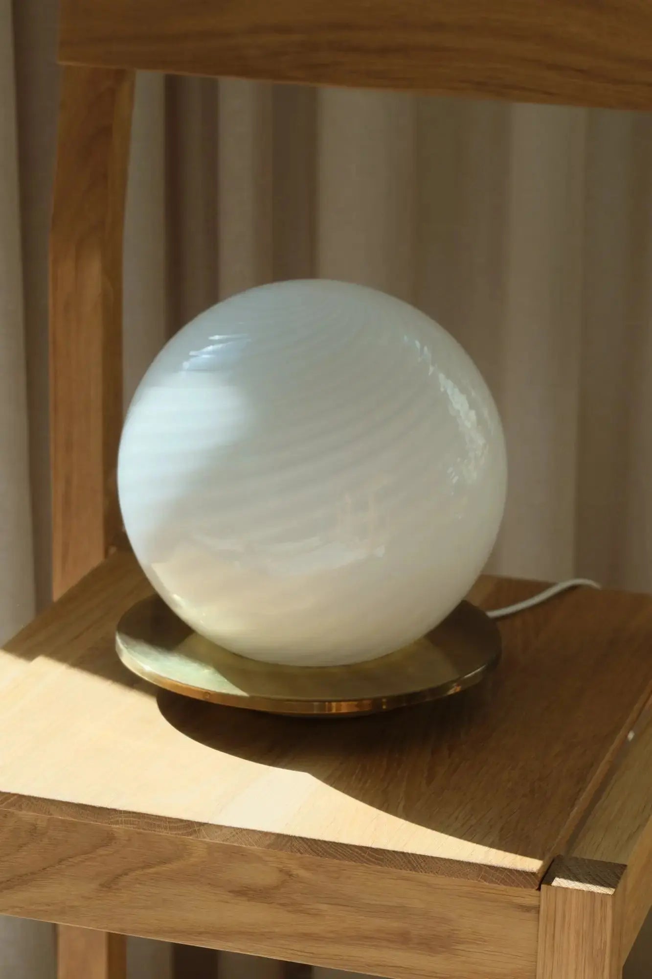 White Murano swirl table lamp with a round brass-coloured metal base from Studio Hafnia
