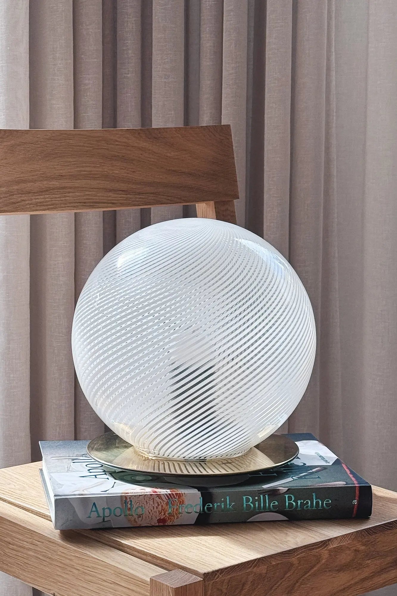 Vintage Murano globe table lamp in white swirl glass with brass base, H25 cm, standing on books on an oak chair