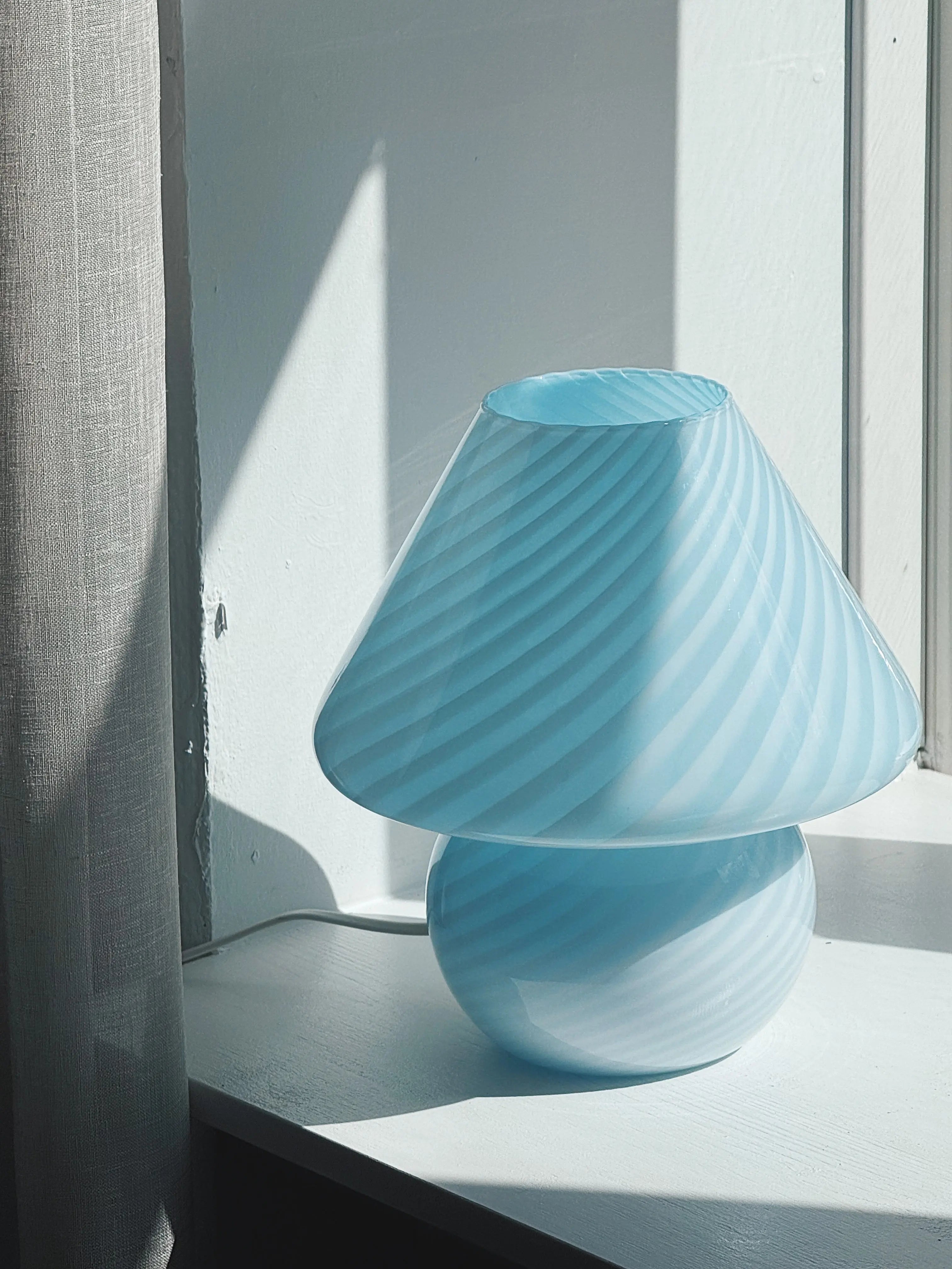 Close-up of the light blue Murano mushroom lamp's swirl pattern and dome shape in backlight