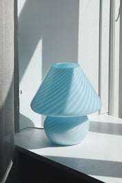 Light blue vintage Murano mushroom table lamp in hand-blown glass with swirl pattern on a white windowsill