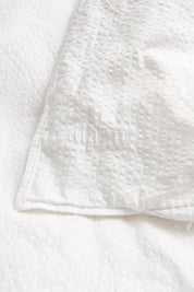 Close-up of the crinkled seersucker weave with the embroidered aiayu logo, white, Studio Hafnia