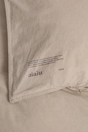 Nærbillede af hjørne og vaskemærke på Aiayu dynebetræk i farven Dried Herb, Studio Hafnia