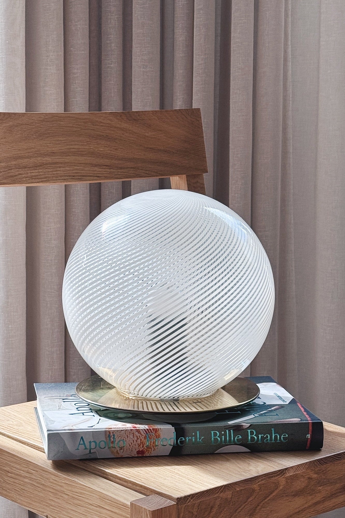 Vintage Murano globe table lamp in white swirl glass with brass base, H25 cm, standing on books on an oak chair