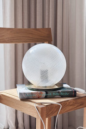 Vintage Murano globe lamp in white swirl glass styled on an oak chair in front of a light curtain