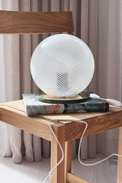 White Murano globe lamp H25 cm seen from the side on a stack of books on an oak chair