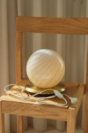 Light yellow Murano swirl globe table lamp with a round brass-coloured metal base from Studio Hafnia